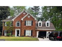 Charming two-story red brick home with black shutters and well-manicured lawn and a two car garage at 1030 San Lacinto Ln, Lawrenceville, GA 30043