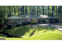 Brick home featuring a carport and lush landscaping, set against a backdrop of mature trees at 1655 Tryon Ne Rd, Brookhaven, GA 30319