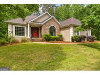 Stunning front exterior with stone accents, red door, manicured lawn, and mature trees, creating great curb appeal at 40 High St, Sharpsburg, GA 30277
