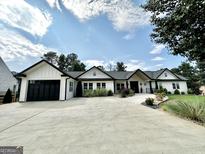 Beautiful white home with black trim, complemented by a well-manicured lawn and a spacious concrete driveway at 3550 N Bogan Rd, Buford, GA 30519