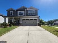 Two-story home with a gray exterior, well-manicured lawn, and a two-car garage on a clear, sunny day at 883 Ironhorse Sw Ln, Mableton, GA 30126
