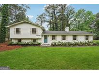 Charming, renovated home features white brick and siding, a bright blue door, and well-manicured landscaping at 4327 Welligton Hill Ln, Snellville, GA 30039