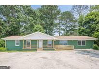 Charming ranch-style home with a painted brick facade, a front porch with wooden railings, and a spacious concrete parking area at 4806 Rockbridge Rd, Stone Mountain, GA 30083