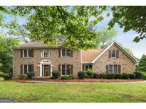Charming two-story brick home with lush green lawn, mature trees, and well-maintained landscaping at 100 Hartford Pl, Fayetteville, GA 30214