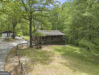 Brick ranch home with a front porch, mature trees, green lawn, and a detached two-car garage at 165 White Rose Ln, Temple, GA 30179