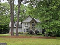 Stately two-story home featuring stone accents, lush landscaping, and mature trees on a sprawling lawn at 80 Jacksons Vly, Sharpsburg, GA 30277