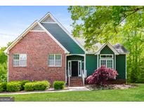 Charming home with brick accents, green siding, and well-manicured front yard, creating inviting curb appeal at 8091 Bouldercrest Pl, Douglasville, GA 30135