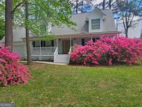 Charming two-story home featuring a welcoming front porch and beautiful blooming bushes at 3979 Doral Cir, Atlanta, GA 30360