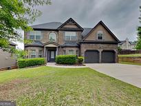 Stunning brick home featuring a manicured lawn, attached two car garage, and charming architectural details at 305 Mango Ct, Mcdonough, GA 30253
