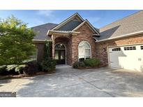 Charming brick home featuring an arched entrance, manicured landscaping, and a concrete driveway at 6504 Cedar Mountain Rd, Douglasville, GA 30134