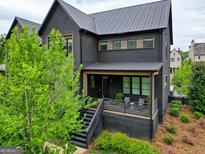 Beautiful modern home with black siding, metal roof, a deck, and professional landscaping at 300 Mado Ln # 329, Chattahoochee Hills, GA 30268