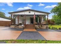 Charming home with a welcoming porch, wagon wheel decor, and a manicured front yard at 80 David Rd, Hampton, GA 30228