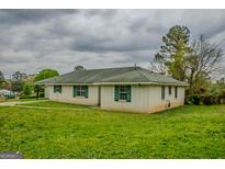 Ranch-style home with a white brick exterior, green shutters, and a well-maintained lawn at 7017 Sun Valley Way, Riverdale, GA 30274