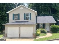 Charming two-story home featuring a two-car garage, neutral siding, and green shutters at 5851 Giles Rd, Lithonia, GA 30058