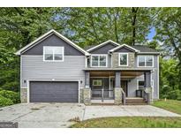 Charming two-story home with gray siding, stone accents, covered porch, and a two-car garage at 1397 Thomas Rd, Decatur, GA 30030