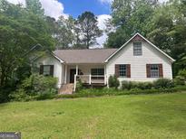 Charming single-Gathering home featuring a large front yard with mature trees, covered porch, and white siding at 128 Kelleytown Woods Dr, Mcdonough, GA 30252