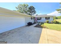 Charming home featuring a garage, an American flag, and a well-maintained front yard at 140 Whitehead Sw Rd, Oxford, GA 30054