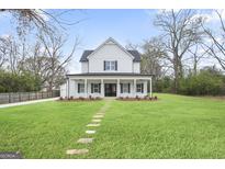 Beautiful two-story farmhouse-style home featuring a welcoming front porch and lush green lawn at 61 Main St, Moreland, GA 30259