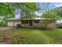 Charming brick home with a well-manicured front yard, mature trees, and a two-car garage at 235 Castlegate Cir, Carrollton, GA 30116