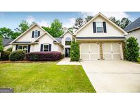 Charming home featuring a two-car garage, complemented by lush green landscaping and manicured bushes at 1015 Buckeye Ln, Villa Rica, GA 30180