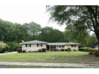 Charming ranch-style home featuring a well-manicured lawn, flowering shrubs, and brick facade at 8672 Bowden St, Douglasville, GA 30134