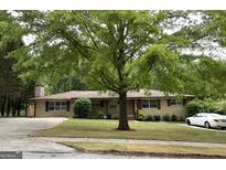 Charming brick ranch home featuring a large tree and well-manicured lawn at 8660 Bowden St, Douglasville, GA 30134