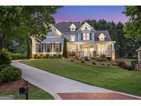 Beautiful two-story home with a well-manicured lawn and inviting front porch at dusk at 8710 Gilmer Ft, Cumming, GA 30028