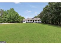 Charming white house featuring a well-manicured lawn and inviting front porch at 138 Sam Solomon Rd, Locust Grove, GA 30248