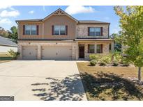 Beautiful two-story home featuring a three-car garage, brick and shingle facade, and a well-manicured front yard at 8069 Louis Dr, Locust Grove, GA 30248