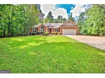 Charming single-story brick home featuring an attached garage, a well-manicured lawn and mature trees at 250 Kari Glen Dr, Fayetteville, GA 30215