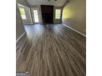Spacious living room featuring a classic fireplace and modern vinyl flooring at 2204 Liberty Sw Ln, Conyers, GA 30094