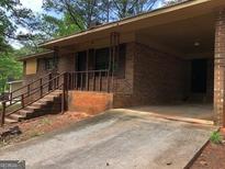A cozy brick home featuring a covered carport and a small front porch at 7225 Pineneedle Sw Dr, Covington, GA 30014