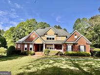Beautiful two-story brick home with manicured lawn, mature trees and classic architectural details at 6680 Bentley Trl, Cumming, GA 30040