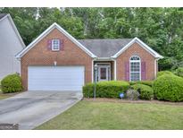 Charming brick home with a two-car garage, manicured lawn, and an ADT security system sign in the yard at 702 Brambling Way, Stockbridge, GA 30281
