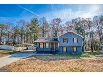 Two-story home featuring a carport, a welcoming front porch, and tasteful landscaping at 1355 Compton Woods Dr, Loganville, GA 30052