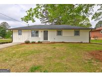 Charming, one-story home with brick accents, a well-manicured lawn, and lush greenery at 7279 Mayfair Cir, Jonesboro, GA 30236