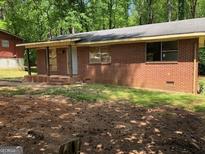 Image of a single-story brick home with a flat roof and small front porch needing repair at 6186 Green Acres Sw Dr, Covington, GA 30014