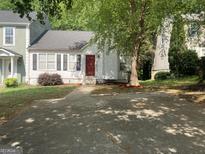 Charming home featuring a red front door, white siding, black shutters, and mature landscaping at 1047 Plantation Nw Way, Kennesaw, GA 30144
