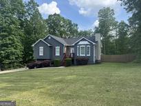 Charming gray home featuring a well-manicured lawn, lush landscaping and inviting curb appeal at 30 Wellington Trl, Covington, GA 30016