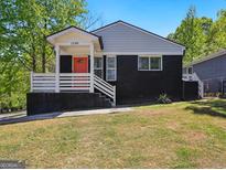 Charming home with a black brick exterior, a welcoming front porch, and a vibrant orange front door at 1599 Ezra Church Nw Dr, Atlanta, GA 30314
