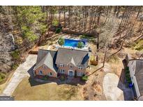 Inviting brick home features a backyard pool nestled within a wooded landscape and a private fenced in yard at 212 Birkhill, Peachtree City, GA 30269