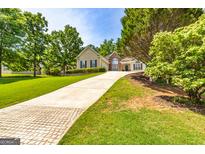 Charming home featuring a well-manicured lawn, beautiful landscaping and a long concrete driveway leading to a two-car garage at 120 Lyndhurst Way, Sharpsburg, GA 30277