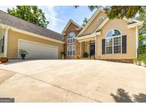 Charming home featuring a manicured lawn, stone accents, and attached two car garage on sunny day at 120 Lyndhurst Way, Sharpsburg, GA 30277