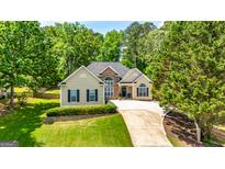 Charming one-story home with a stone-accented facade and meticulously landscaped front yard with a winding driveway at 120 Lyndhurst Way, Sharpsburg, GA 30277