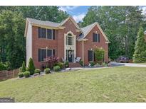 Beautiful brick home featuring a well-manicured lawn and lush landscaping at 4410 Red Rock Pt, Suwanee, GA 30024
