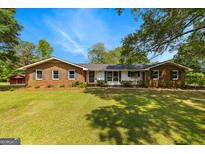 Charming single-story brick home with a lush lawn and mature trees creating a peaceful setting at 270 Lake Cir, Fayetteville, GA 30215