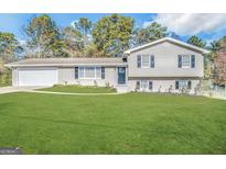 Charming split-level home with gray brick, mature trees and an expansive green lawn at 5906 Pine Hurst Way, Douglasville, GA 30135