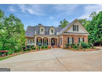 Stately brick home with a circular driveway, manicured landscaping, and charming balcony details at 95 Weslyan Way, Oxford, GA 30054