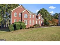 Charming two-story red brick home featuring a well-manicured lawn and mature landscaping at 176 Fairoaks Cir, Stockbridge, GA 30281