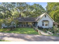 Charming single-story home with a lush front lawn and mature trees under a clear blue sky at 2371 Leguin Mill Rd, Locust Grove, GA 30248